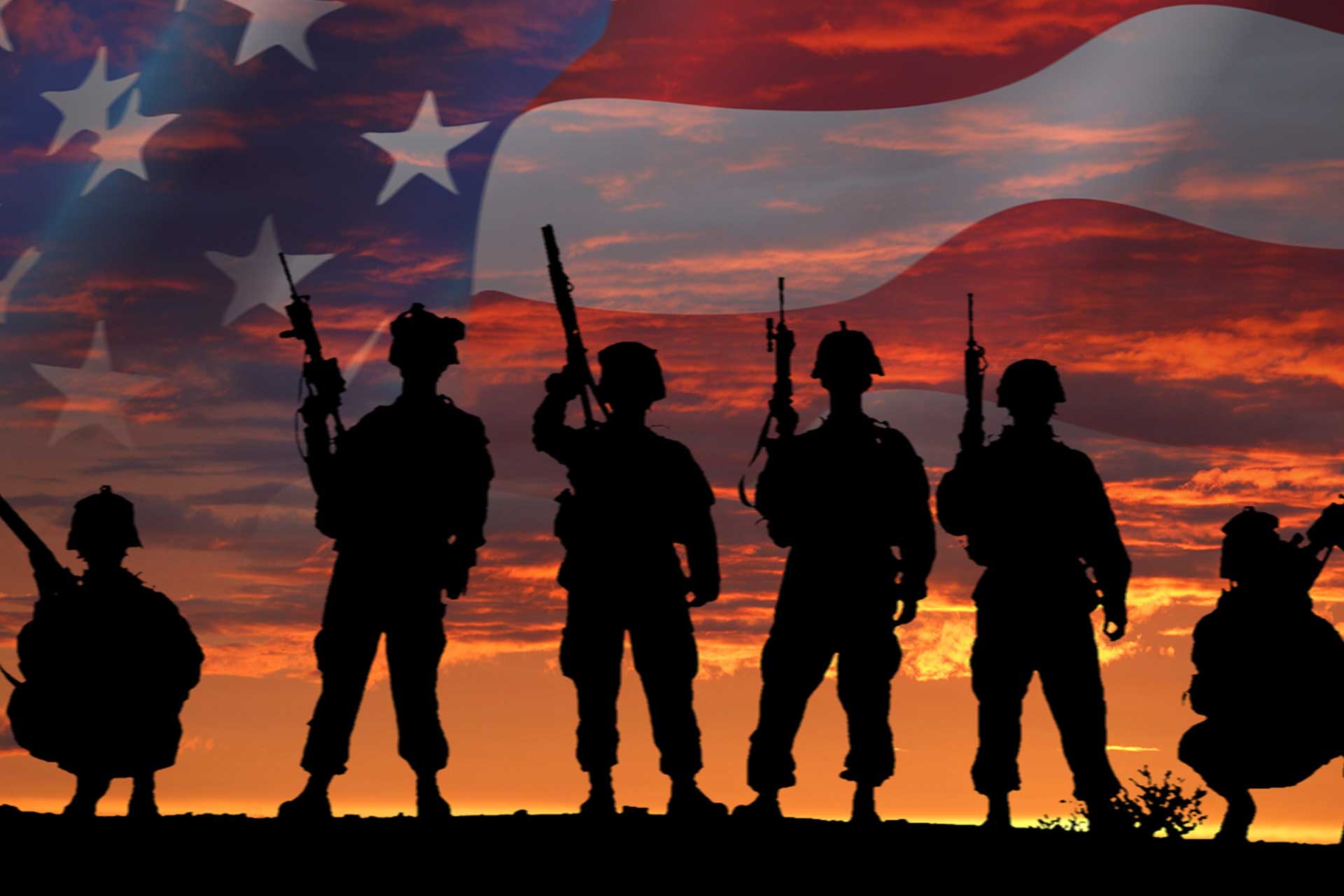 Soldiers stand at sunset in front of American flag